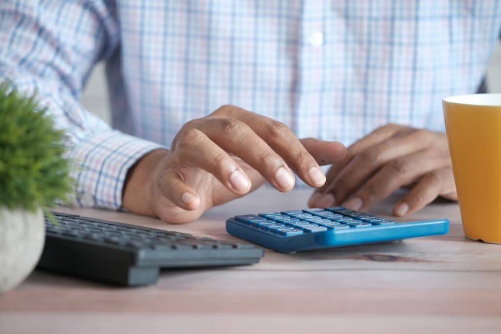 photo of man using calculator to represent consideration of various business loans and debt financing options