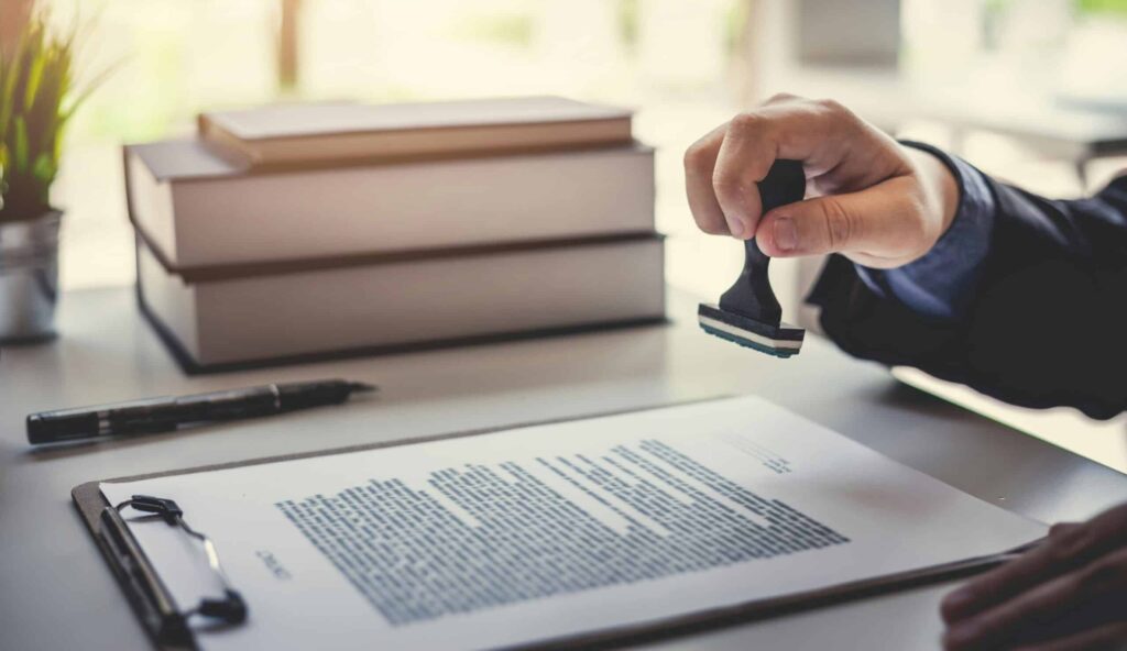 A person stamping a contract with a notary seal, representing contract law for business owners in Ontario