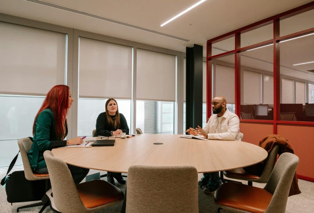 Group of coworkers around a boardroom table, representing mediation and workplace investigations in Ontario