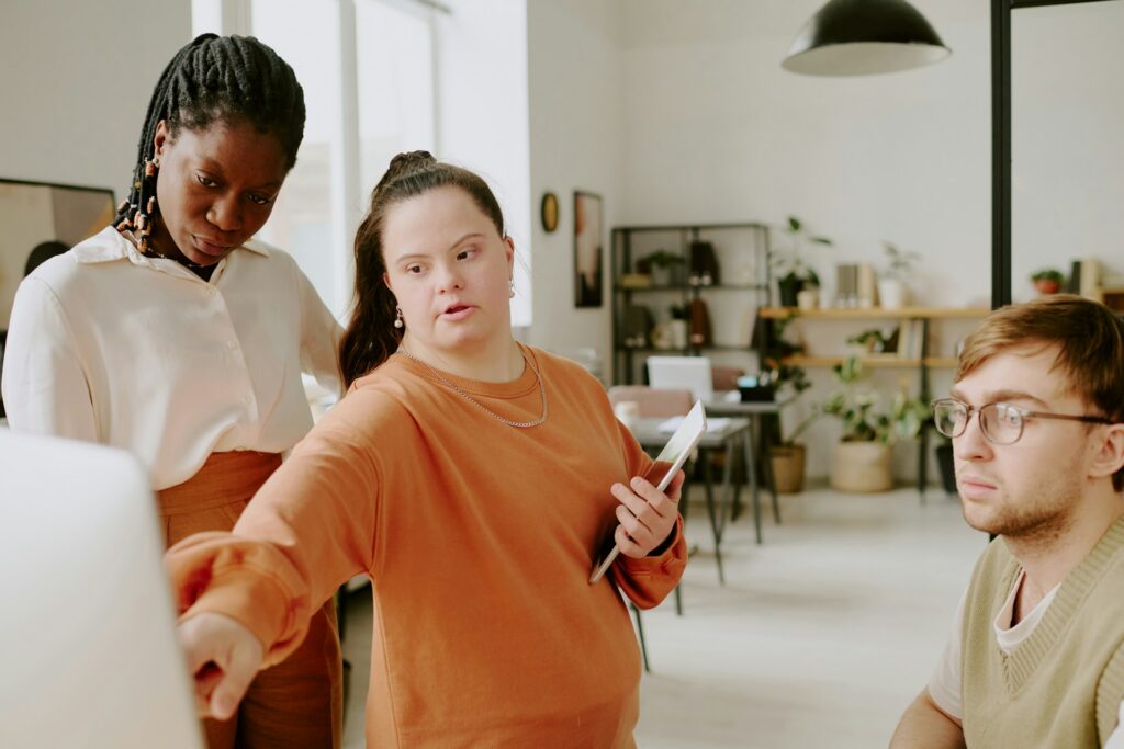 An employee with a visible disability pointing to a workplace computer highlighting the importance of Ontario employers complying with AODA accessibility laws.