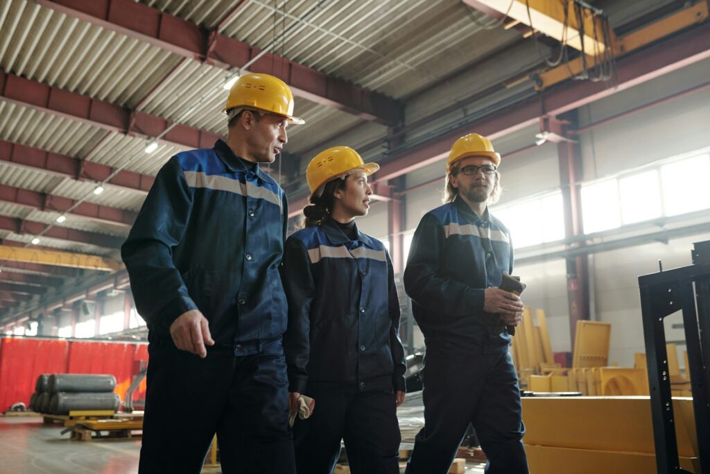 Three industrial workers walking through a worksite together, representing the union organization process and what Ontario employers can and cannot say during unionization.
