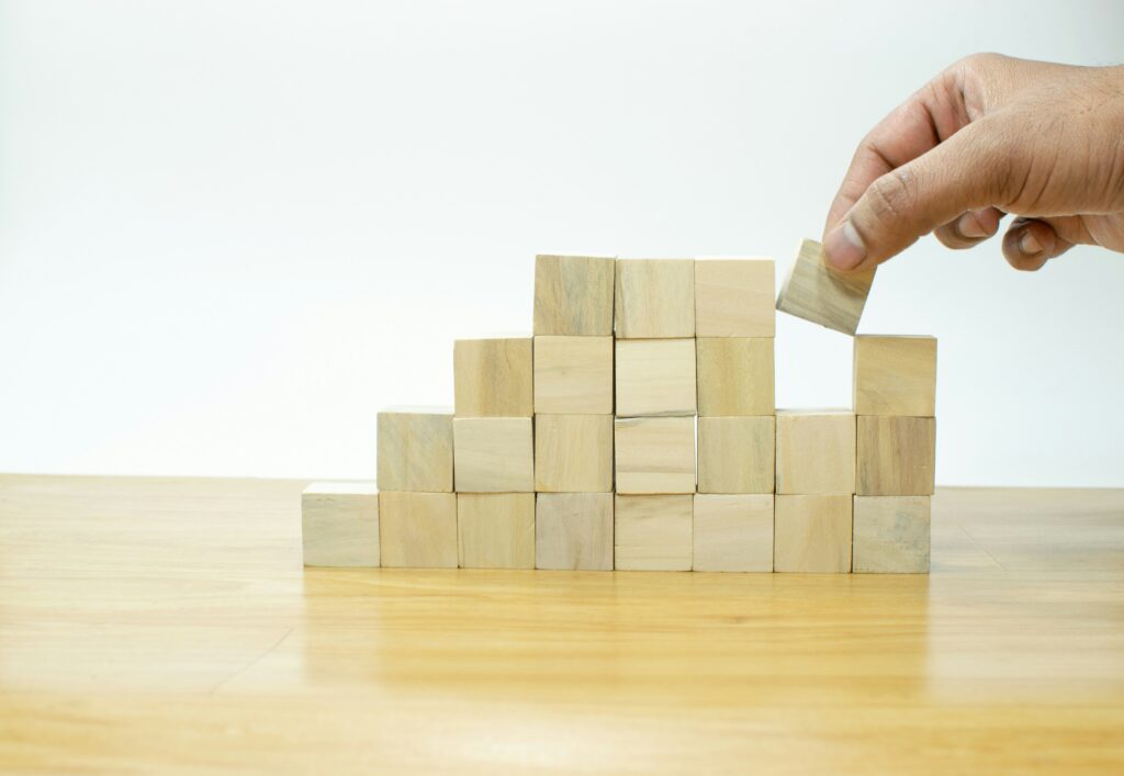 A person placing a block into a stack of wood boxes, representing fixed-term employment contract risks for Windsor employers.